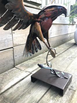 Een metalen kunstwerk van een adelaar die een vis vangt, 'IRON EAGLE'